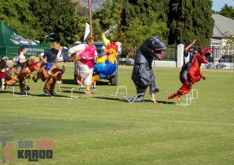 Volkskool personeel wys hul spiere by die Dinosour Obstacle Course
